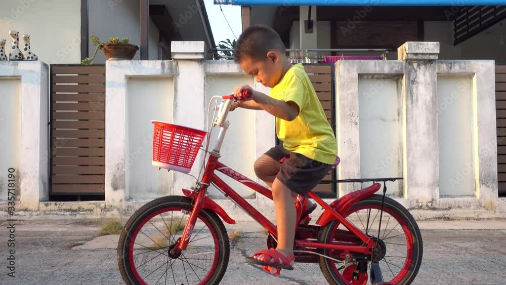 Asian cute cheerful little child boy playful funny bike bicycle at asphalt road in Housing estate at sunset, Video 4K resolution Asian cute cheerful little child boy playful funny bike bicycle at asphalt road in Housing estate at sunset, Video 4K resolution