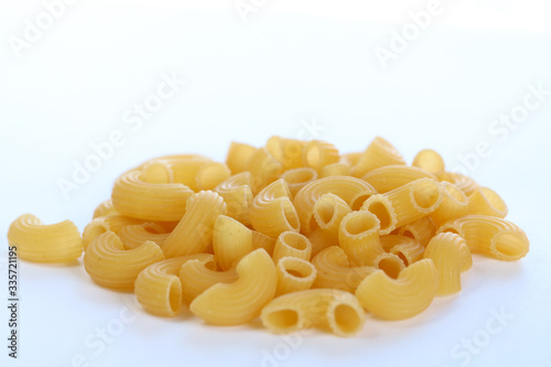 A bunch of dry macaroni pasta  on white background. Side view, copy space