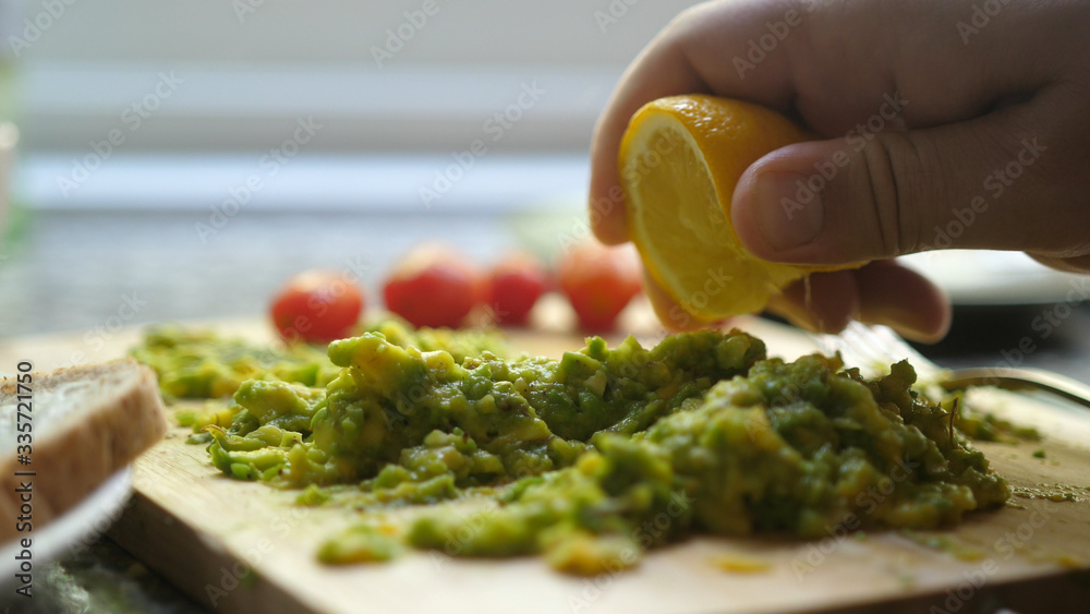 Close up Of Hand Squeezes Lemon Juice Over Avocado Toast. Breakfast Time, Healthy Food. Close up Of Hand Squeezes Lemon Juice Over Avocado Toast. Breakfast Time, Healthy Food.