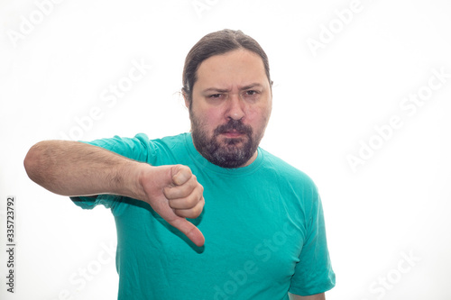 Middle-aged man in a T-shirt shows a thumb down gesture. Isolated on a white background.