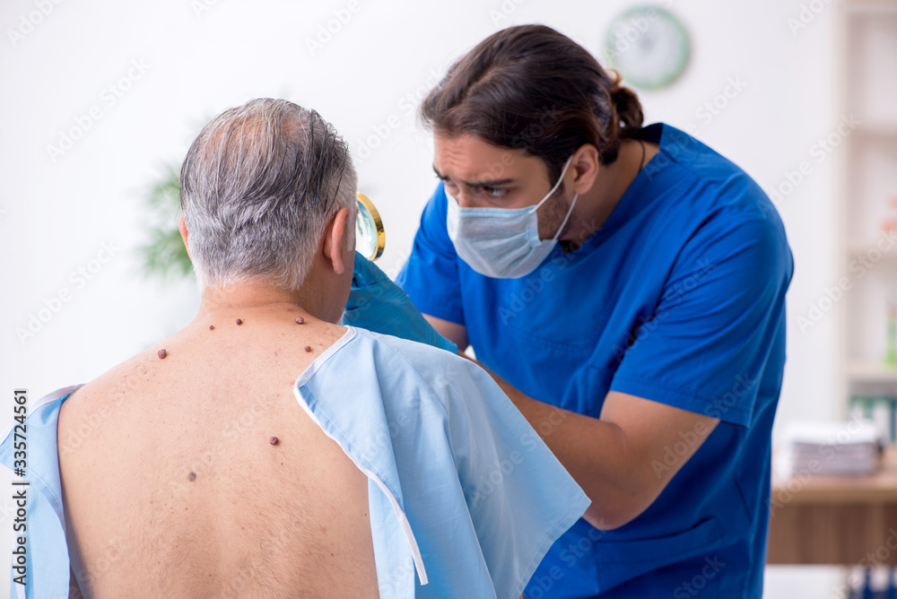 Fototapeta premium Old man visiting young male doctor dermatologist