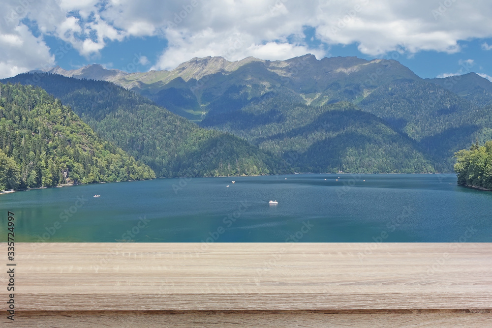empty wooden table against the backdrop of mountains and a lake.