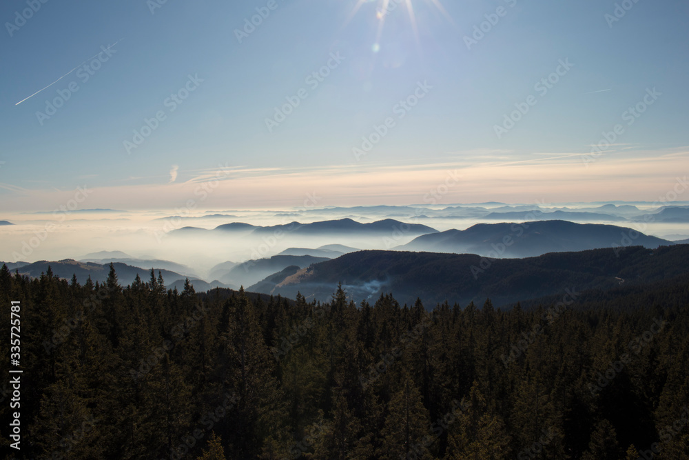 Obraz premium View over Rogla shot from the Tree Tops Walk. Beautiful view of the cloudy skyes and forest in Pohorje in Slovenia. Popular tourist attraction and viewpoint.