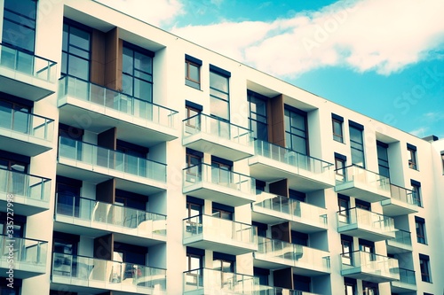 Exterior of new apartment buildings on a blue cloudy sky background. No people. Real estate business concept. Retro stylized colorful tonal filter effect.