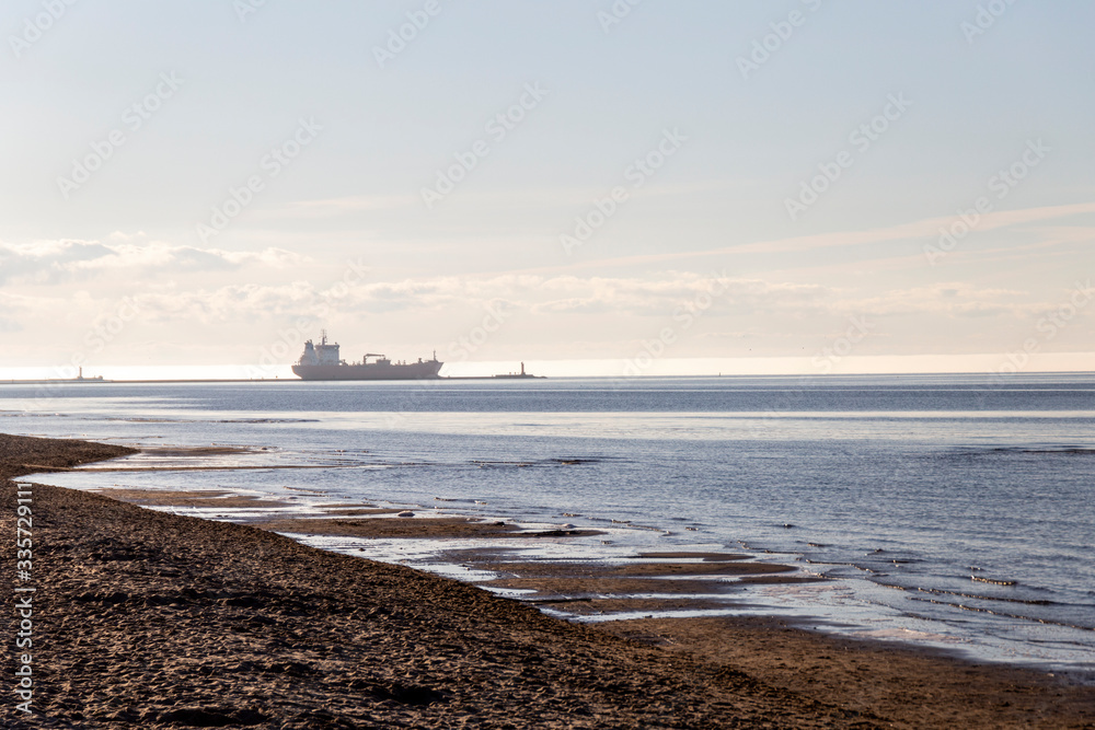 Tanker in the Gulf of Riga on a sunny day and people on the beach.