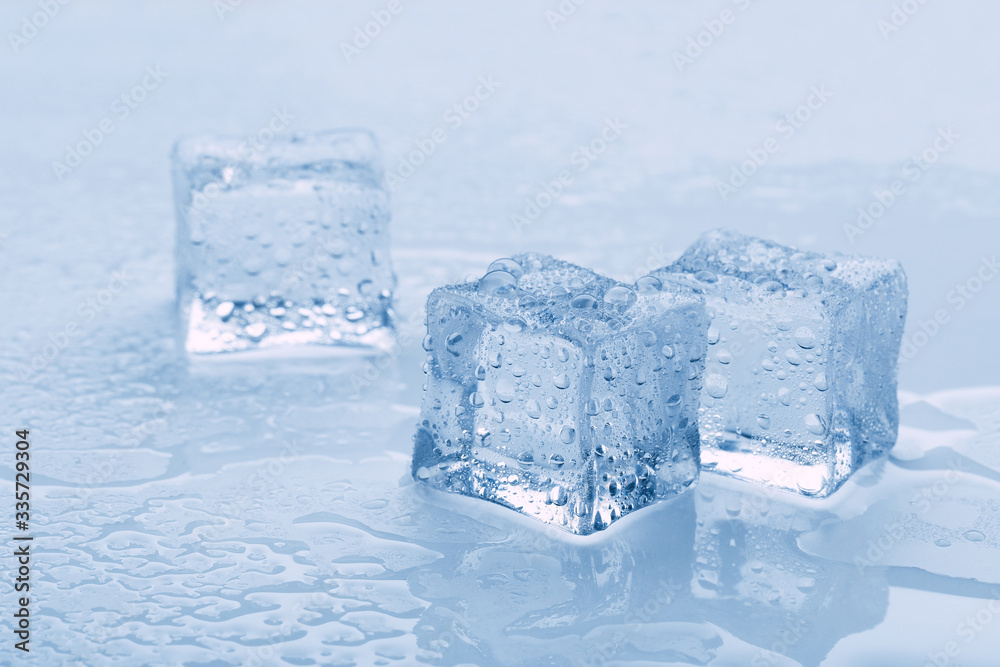 several melted ice cubes with drops on a light background with blue tinting several melted ice cubes with drops on a light background with blue tinting