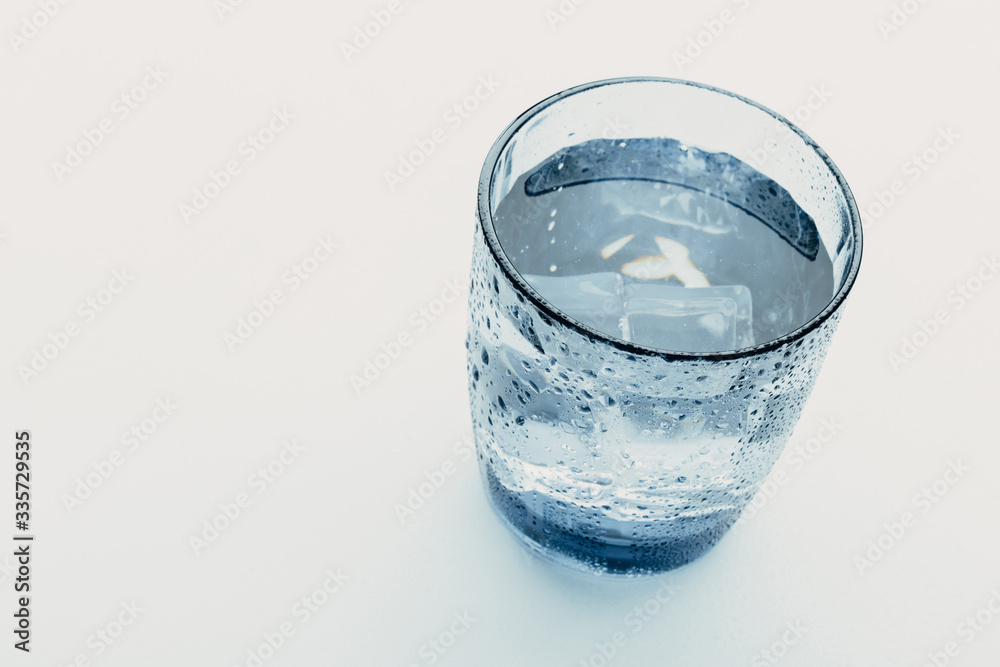 glass of water with ice cubes on a light background. glass of water with ice cubes on a light background.