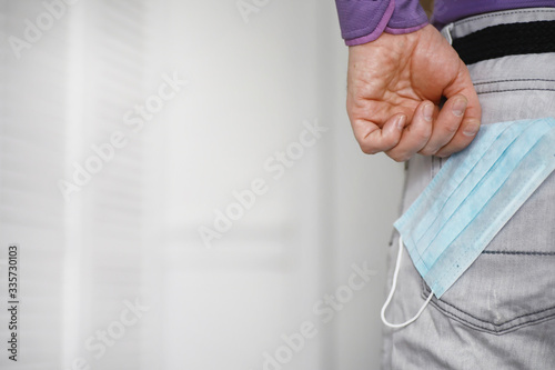 A disposable medical mask sticks out of a pocket instead of a napkin. A man with a disposable mask in a suit and jeans. Individual respiratory protection.