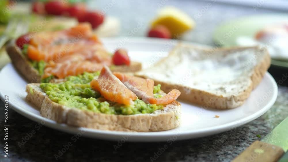 Cooking Toasts with avocado, and smoked salmon on the white plate. slow motion Cooking Toasts with avocado, and smoked salmon on the white plate. slow motion