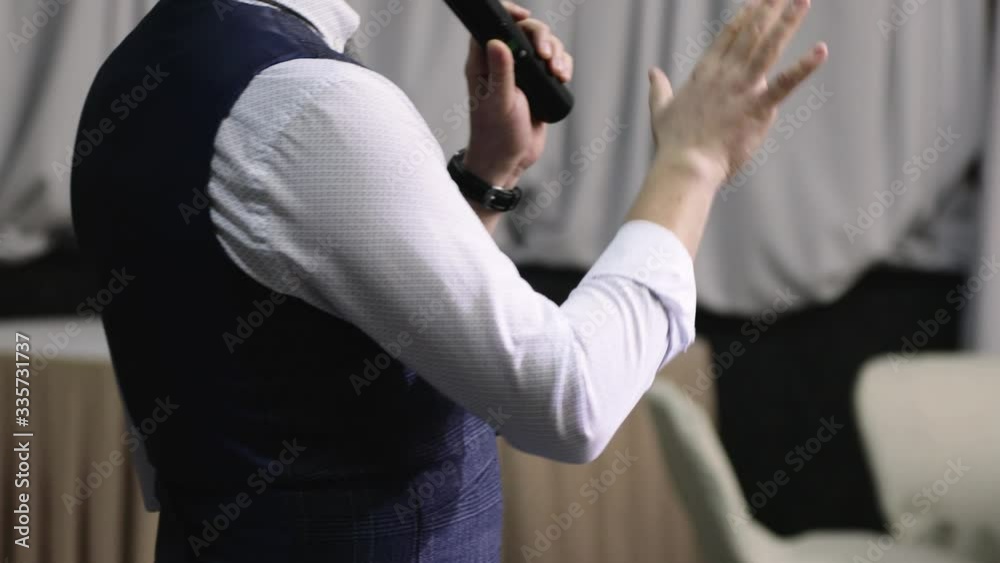 Orator man with microphone speaks in front of the audience vigorously gesturing