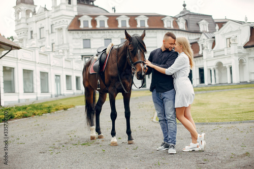 Couple in a summer rainy park. Pair standing with a horse. Girl in a white dress