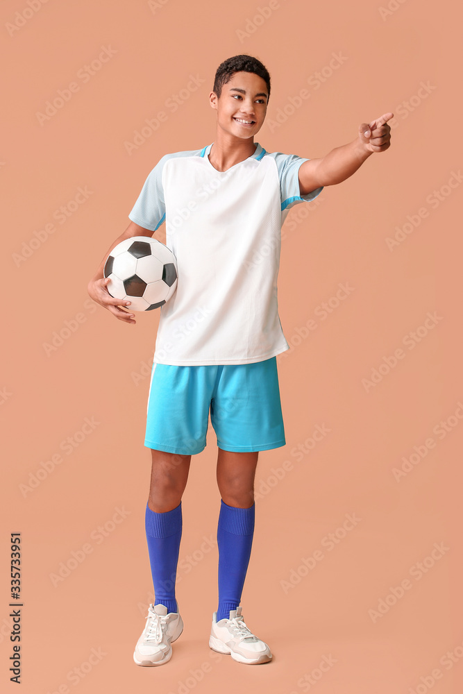 Young African-American football player pointing at something on color background Young African-American football player pointing at something on color background