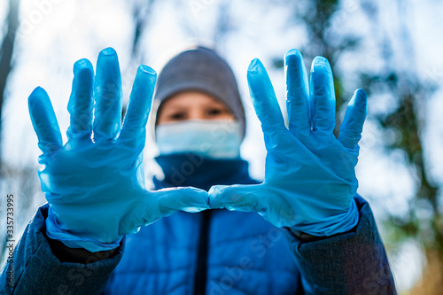 Schoolboy in medical rubber gloves and face mask.Teenage shows two palms in stop sign in front of camera. Stop the coronavirus. Pandemic. COVID-19, corona virus epidemic, infection, quarantine, virus. photo