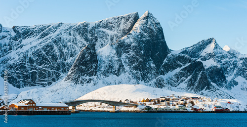 Buildings and bridge in front of snow covered mountains, Norway.