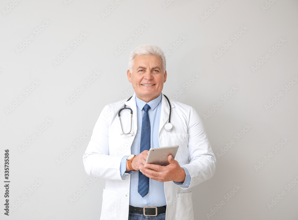 Portrait of male doctor with tablet computer on grey background Portrait of male doctor with tablet computer on grey background