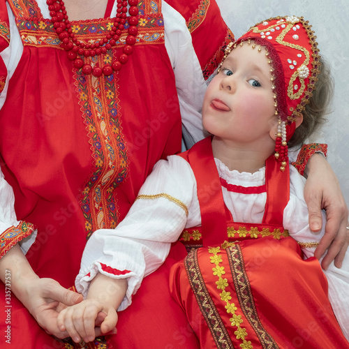 Child girl in Russian national costume sundress and kokoshnik. The child shows the tongue, prank. National traditions and culture