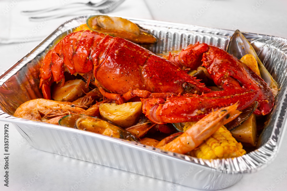 A view of a tin container of lobster boil, in a restaurant or kitchen setting. A view of a tin container of lobster boil, in a restaurant or kitchen setting.