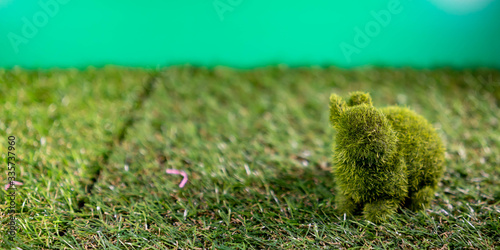 Rabbit made of grass while sitting on a grass and green background for happy easter celebration © Bill