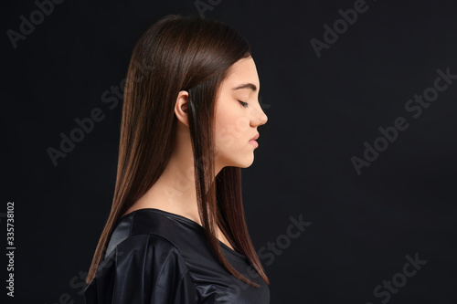 Young woman with beautiful straight hair on dark background