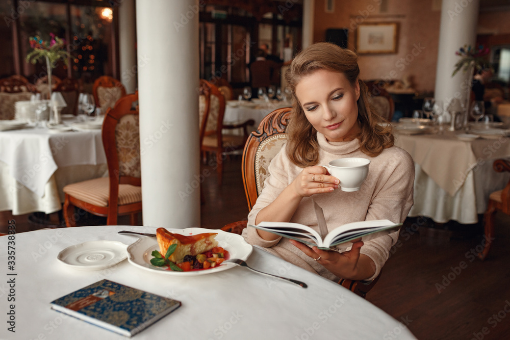 Beautiful young woman reading a book in restaurant during her break. Beautiful young woman reading a book in restaurant during her break.
