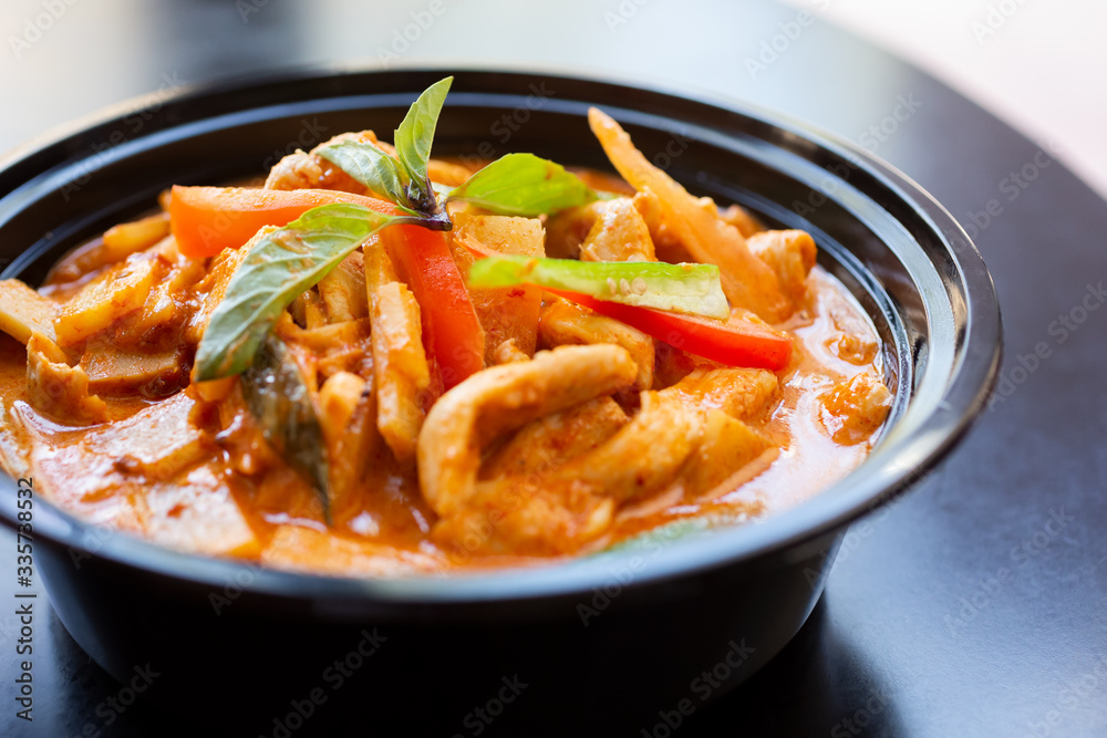 A view of a bowl of red curry, in a restaurant or kitchen setting.