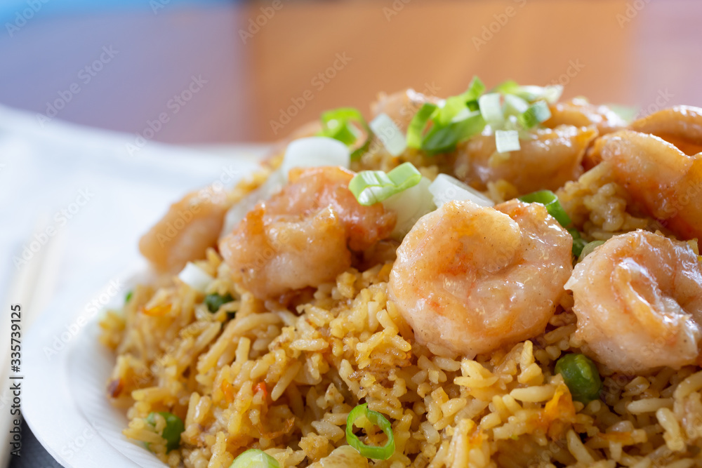 A closeup view of a plate of shrimp fried rice, in a restaurant or kitchen setting.