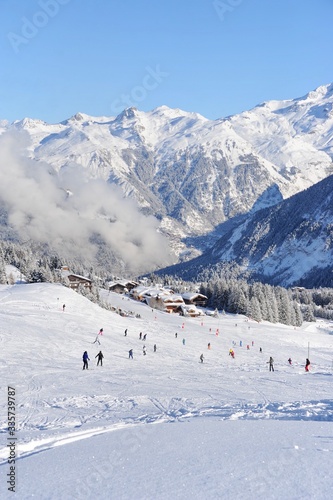 Ski resort Courchevel in European Alps, with skiing people and chalets under the clouds in winter. Courchevel is one of the best resort and most famous one with it’s wide range of ski slopes. 