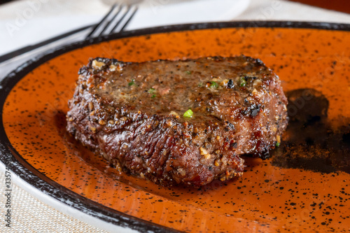 A closeup view of a cut of top sirloin steak on a plate in a restaurant or kitchen setting.