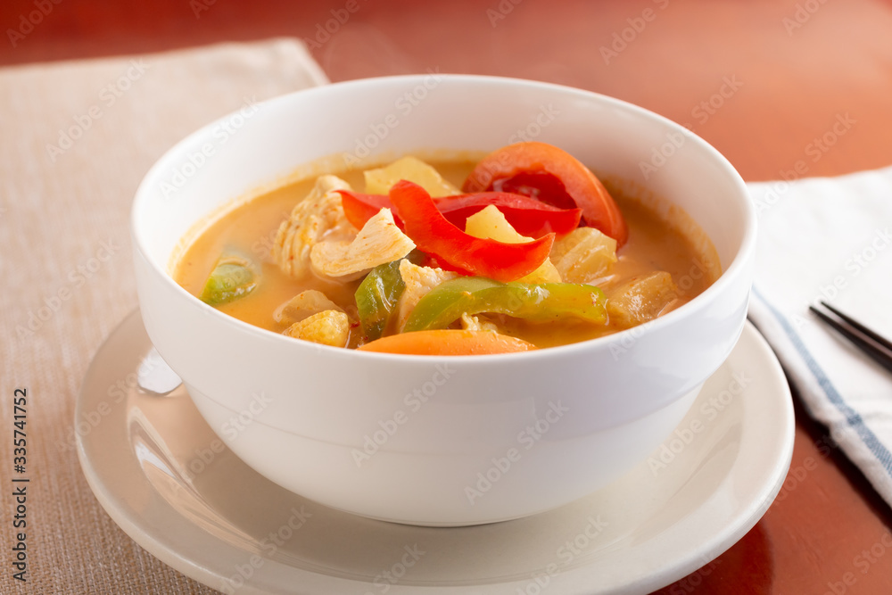 A view of a bowl of pineapple curry on display in a restaurant or kitchen setting. A view of a bowl of pineapple curry on display in a restaurant or kitchen setting.