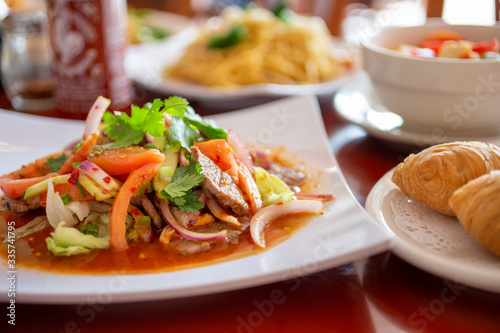 A view of several prepared dishes in a restaurant setting, featuring a Thai beef salad dish.