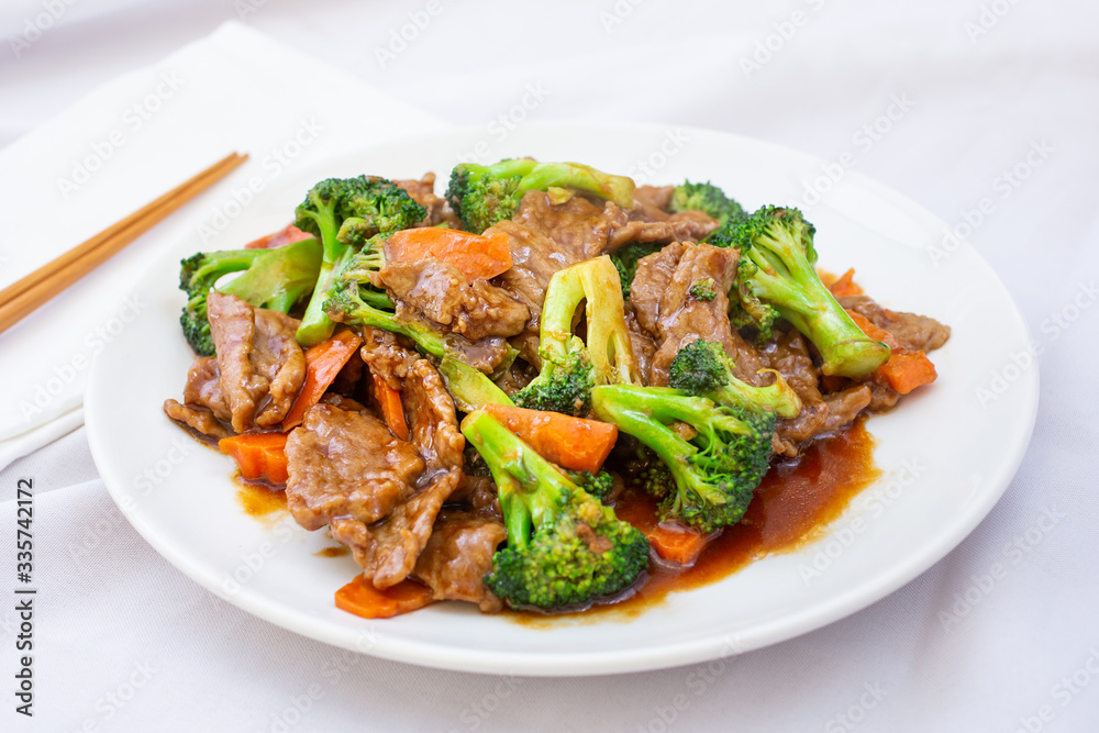 A view of a Chinese plate of beef and broccoli, in a restaurant or kitchen setting.