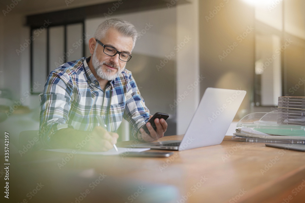 Man working from home with laptop and smartphone - obrazy, fototapety, plakaty 