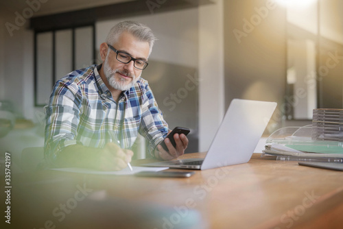 Man working from home with laptop and smartphone