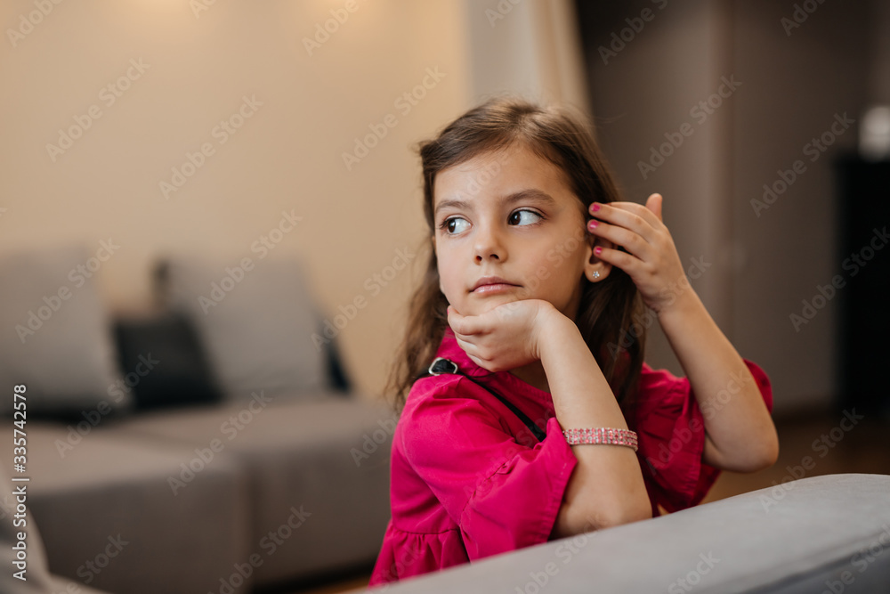 beautiful little girl. little fashion girl portrait in home interior. girl in a pink dress, a bracelet, with pink nails. beautiful little girl. little fashion girl portrait in home interior. girl in a pink dress, a bracelet, with pink nails.