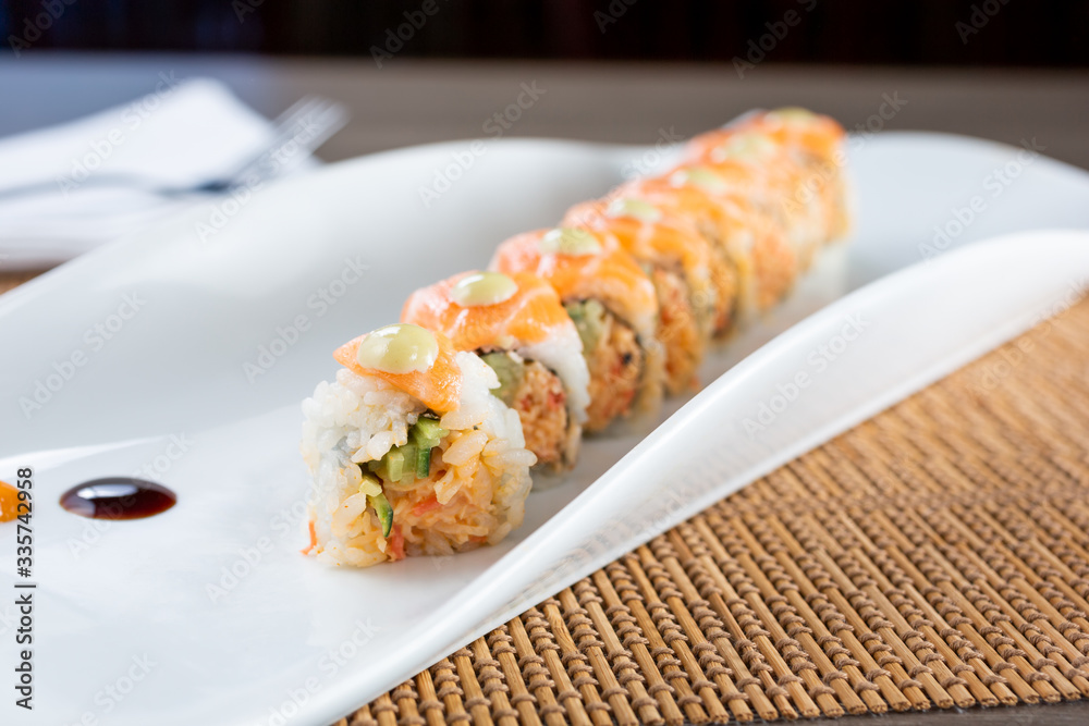 A view of an orange dragon roll sushi plate, in a restaurant or kitchen setting. A view of an orange dragon roll sushi plate, in a restaurant or kitchen setting.