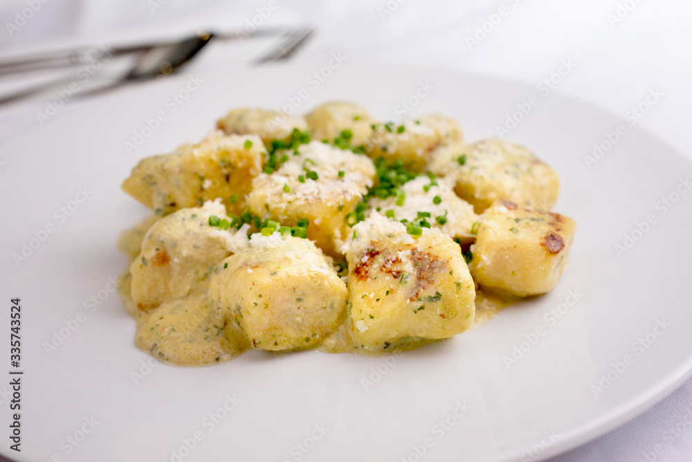 A closeup view of a plate of gnocchi, in a restaurant or kitchen setting. A closeup view of a plate of gnocchi, in a restaurant or kitchen setting.