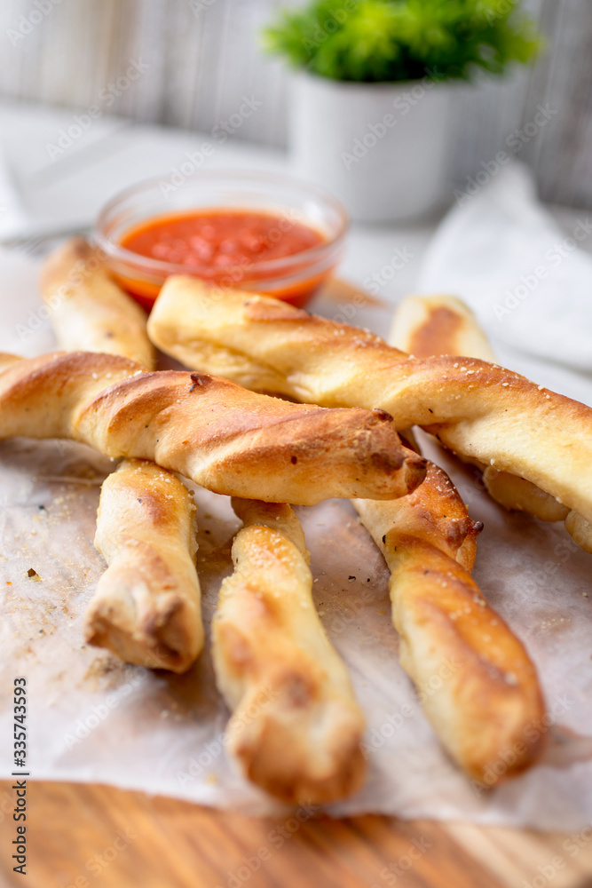 A closeup view of a wooden board of twirling or twisted breadsticks, in a restaurant or kitchen setting. A closeup view of a wooden board of twirling or twisted breadsticks, in a restaurant or kitchen setting.