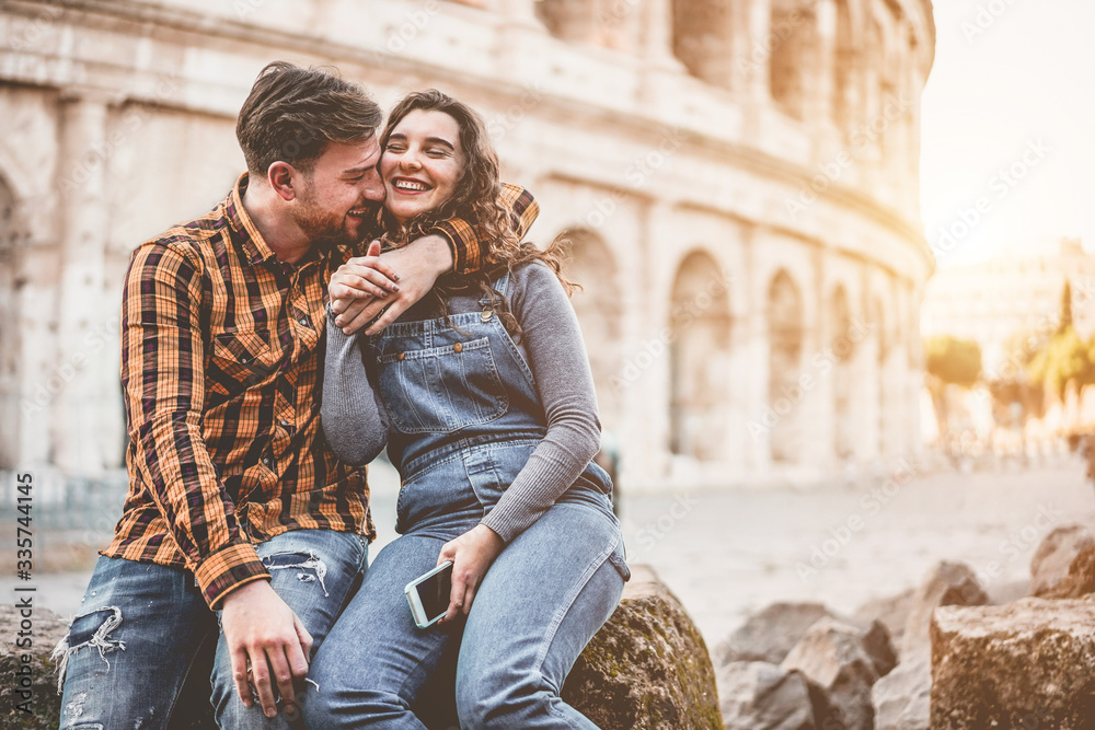 Young couple having tender moments in Rome with Colosseum as background - Lovers having fun during europe vacation tour - Travel, love and romance concept - Focus on faces