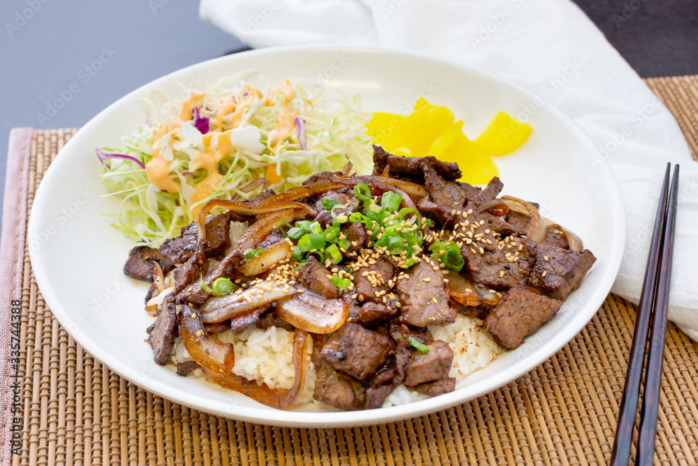 A view of a teriyaki beef plate, in a restaurant or kitchen setting.