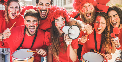 Red sport fans screaming while supporting their team out of the stadium - Football people supporters having fun at competion event - Champions, betting and winning concept - Focus on center girl face