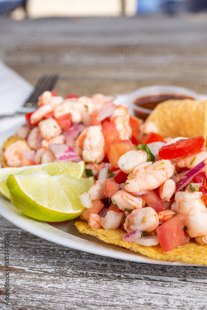 A closeup view of a plate of shrimp ceviche tostadas, in a restaurant or kitchen setting.