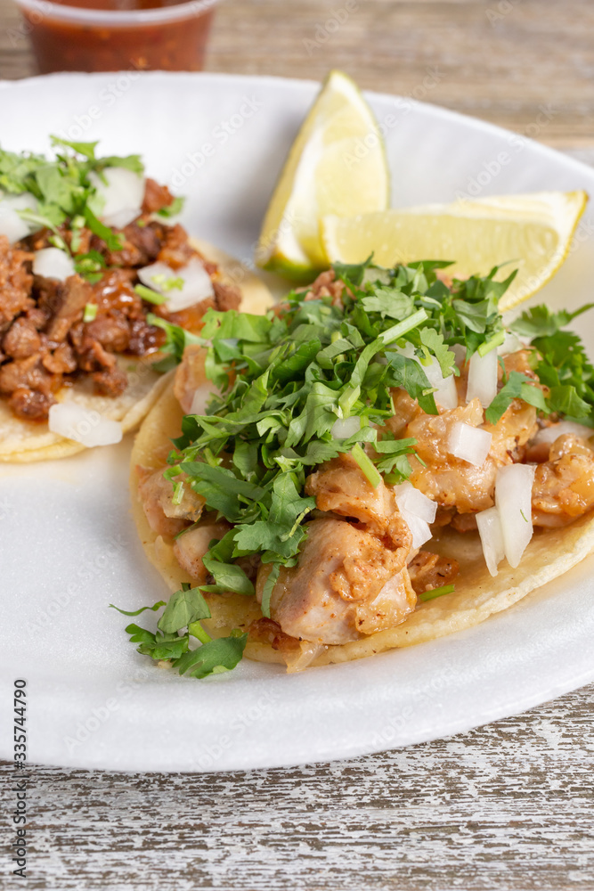 A view of a chicken taco and a carne asada taco, in a restaurant or kitchen setting.