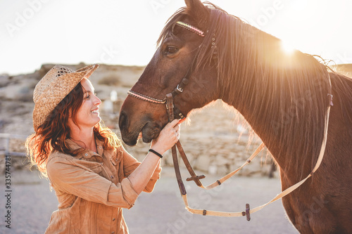 Young farmer woman playing with her bitless horse in a sunny day inside corral ranch - Concept about love between people and animals - Focus on girl face