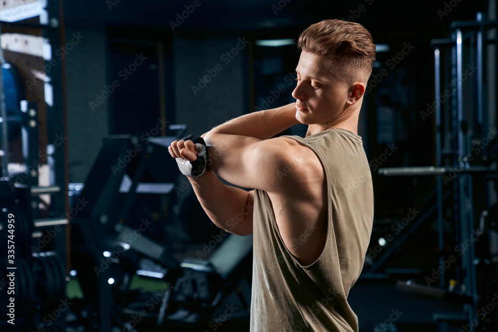 Bodybuilder stretching armsin gym. Bodybuilder stretching armsin gym.