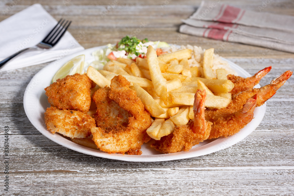A view of a plate of deep fried shrimp with a side of french fries, in a restaurant or kitchen setting. A view of a plate of deep fried shrimp with a side of french fries, in a restaurant or kitchen setting.