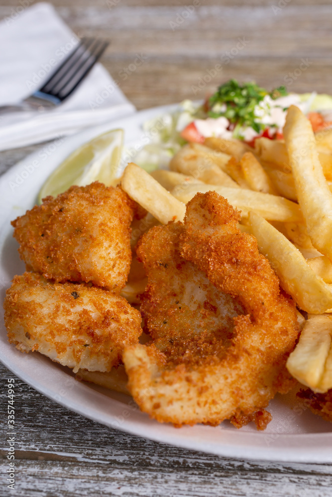 A closeup view of a deep fried shrimp plate, with a side of french fries, in a restaurant or kitchen setting. A closeup view of a deep fried shrimp plate, with a side of french fries, in a restaurant or kitchen setting.