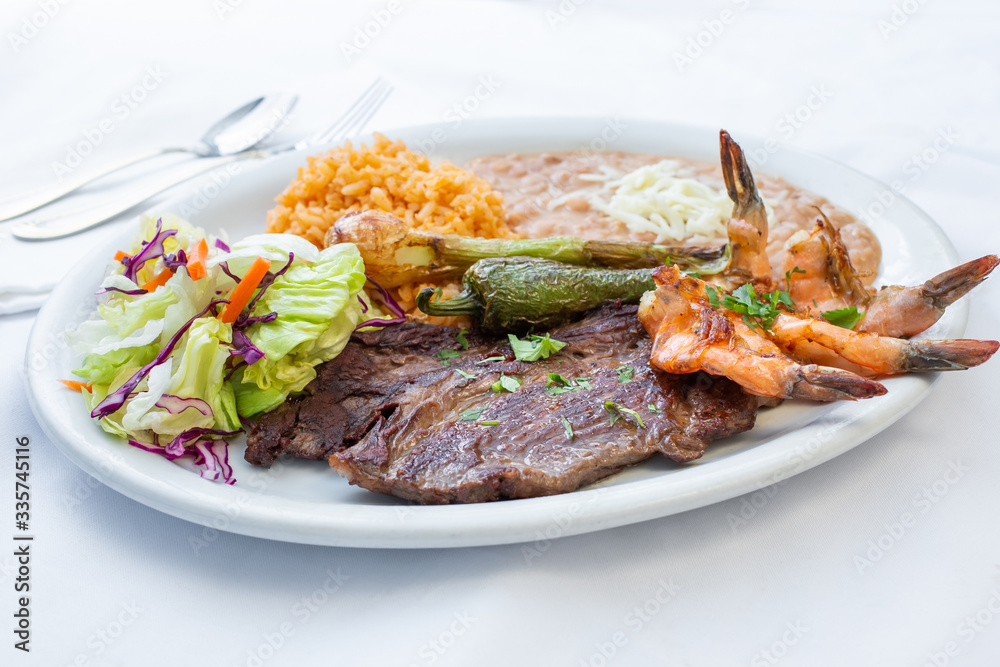 A view of a plate of Mexican surf and turf, in a restaurant or kitchen setting.