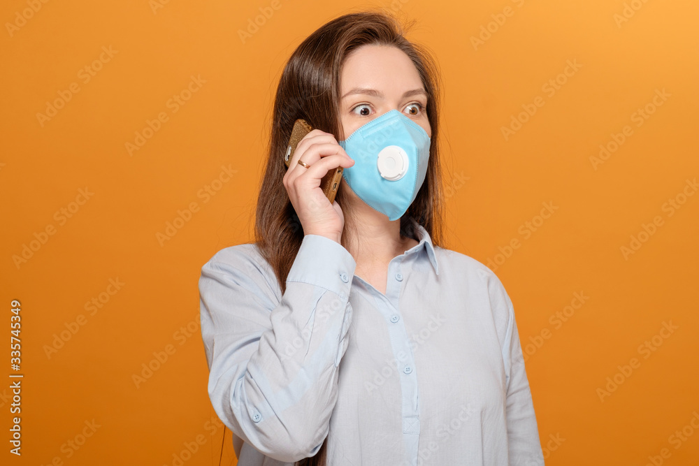 scared young woman with medical mask on her face looks at phone, woman in panic over epidemic, talking on the phone scared young woman with medical mask on her face looks at phone, woman in panic over epidemic, talking on the phone