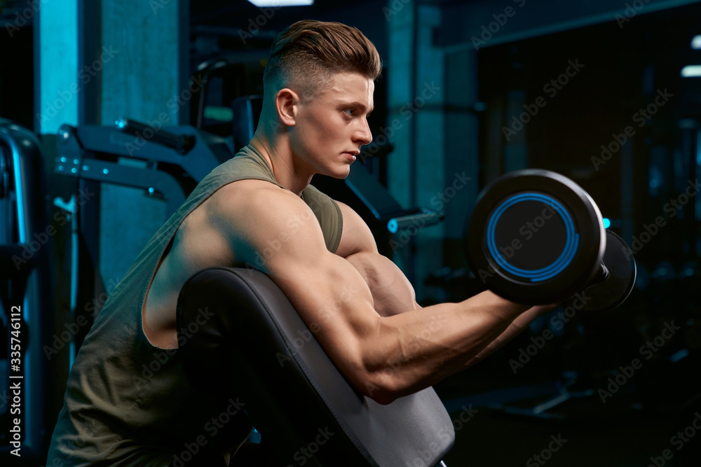 Muscular sportsman building biceps with barbell. Muscular sportsman building biceps with barbell.