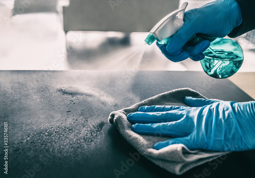 Surface sanitizing against COVID-19 outbreak. Home cleaning spraying antibacterial spray bottle disinfecting against coronavirus wearing nitrile gloves. Sanitize hospital surfaces prevention. photo
